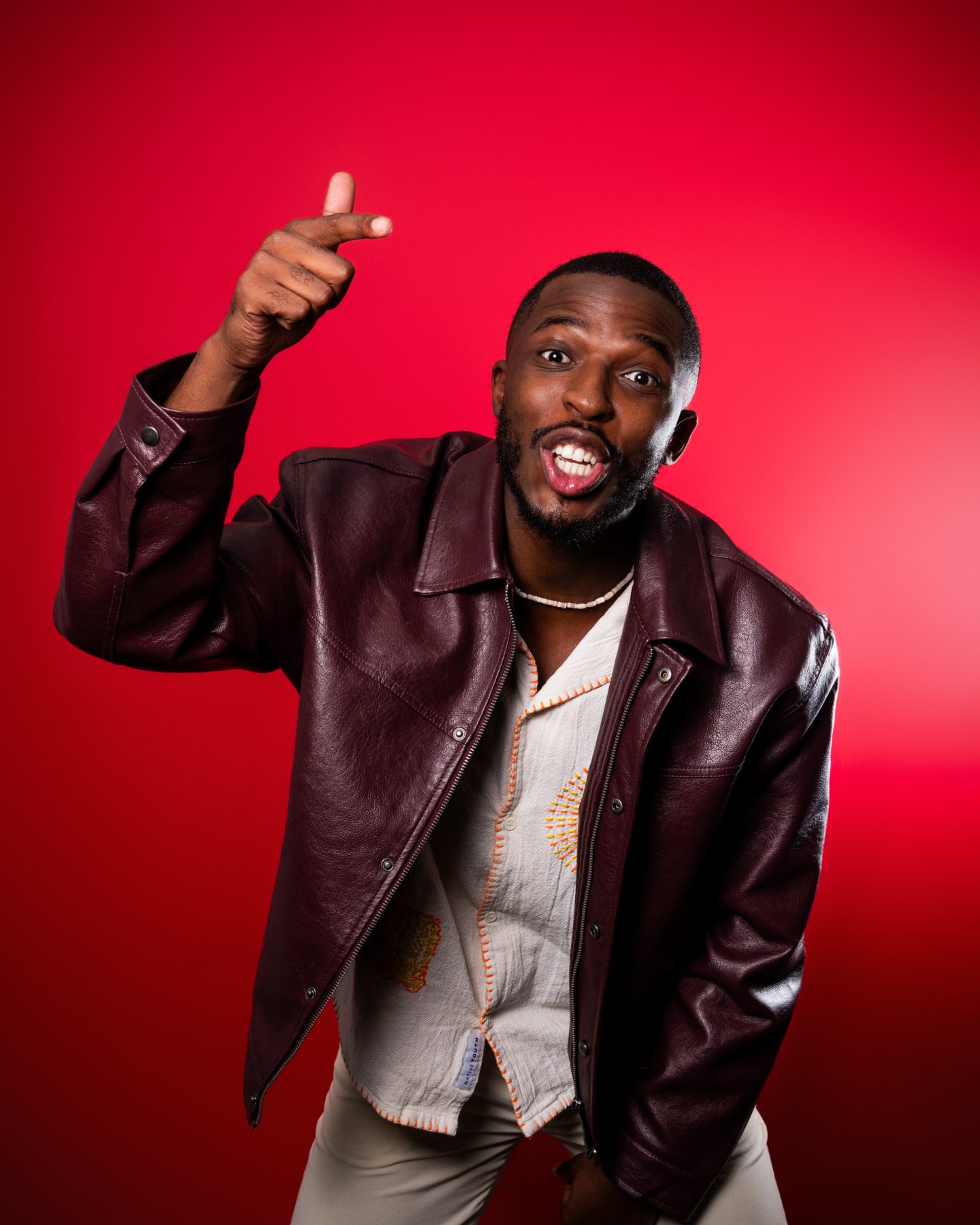 Washington pointing up and grinning on a red backdrop